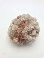 Una piccola ROSETTA DI ARAGONITE di quarzo sopra una superficie bianca.