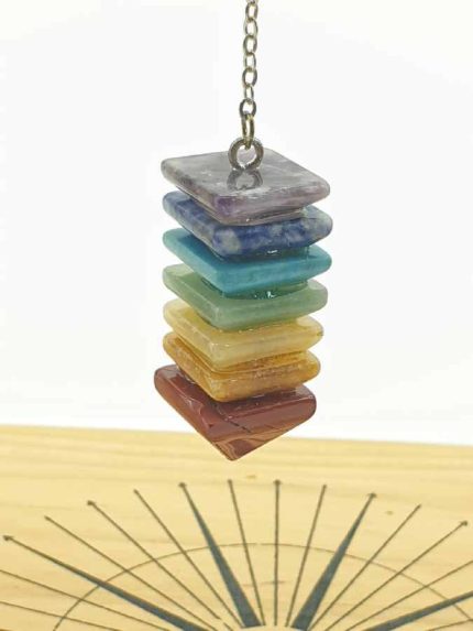 PENDULUM SEVEN CHAKRA PYRAMID BALANCE necklace in bright colors of the rainbow, suspended from a wooden compass, representing balance.