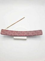 A pink incense stick on a white backing emits a fragrant scent of RED SOAPSTONE INCENSE BURNER.