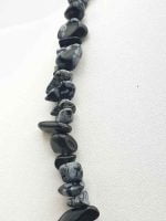 A MEN'S OBSIDIAN SNOWFLAKE CHIPS NECKLACE GIVES BALANCE with black obsidian stones on a white background.