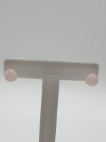A pair of 8 mm rose quartz earrings in sterling silver on a white stand.