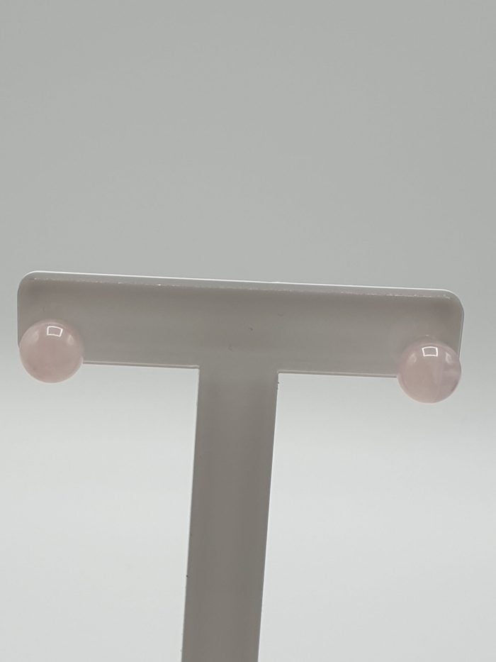 A pair of 8 mm rose quartz earrings in sterling silver on a white stand.