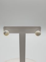 Pair of white stud earrings on a stand made of mother-of-pearl and silver.