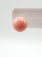 Un orecchino di ORECCHINI CORALLO ROSA IN ARGENTO adagiato su una superficie bianca.