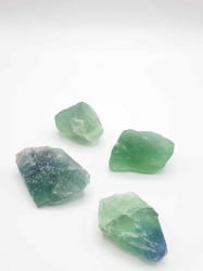 Quattro pezzi di FLUORITE ARCOBALENO GREZZA verde e blu su fondo bianco.