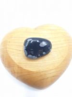An obsidian stone tumbled snowflakes in a heart-shaped wooden box.