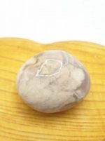 A TUMBLED CHERRY BLOSSOM SAKURA stone on a wooden surface with sakura flowers.