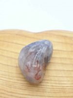 Una piccola pietra di Iolite Burattata seduta sopra una tavola di legno.