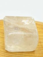 Piece of YELLOW TUMBLED ULEXITE resting on a wooden surface.