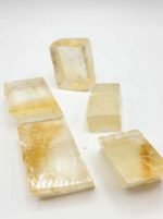 Quattro CUBI DI CALCITE DORATA su fondo bianco.