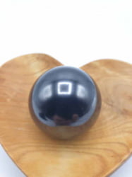 SFERA DI SHUNGITE 4 CM in Shungite appoggiata sopra un cuore di legno.