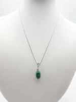 Una collana CIONDOLO PENDENTE DI MALACHITE adorna con grazia un manichino.