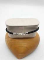 A BRACCIALE DA UOMO CON ONICE NERO, DIASPRO ROSSO E CORDINO CUOIO NERO esposto su una scatola di legno.