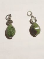Two oval ruby zoisite pendants on a white surface.