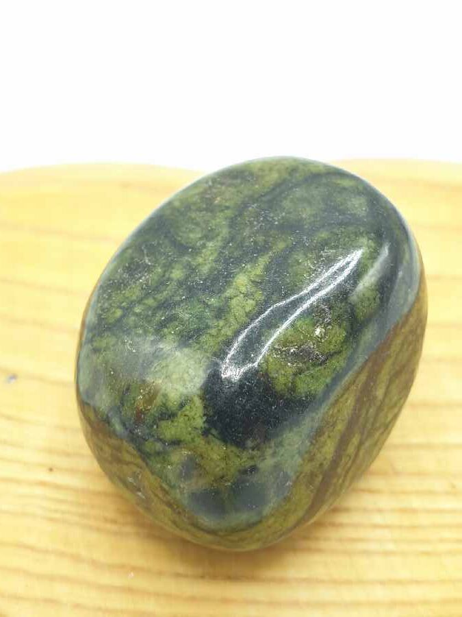 Una pietra di diaspro verde su una tavola di legno.
