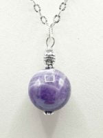A SPHERE AMETHYST PENDANT PENDANT on a silver chain.