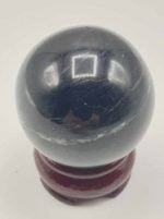 A Black Tourmaline Sphere on a wooden stand.