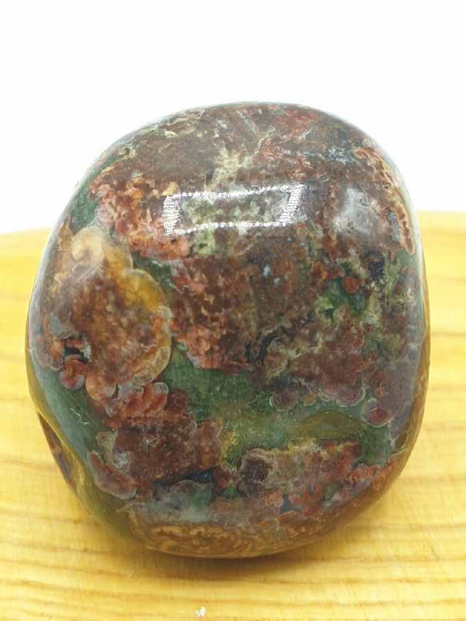 Un pezzo di diaspro verde e marrone su un tavolo di legno.