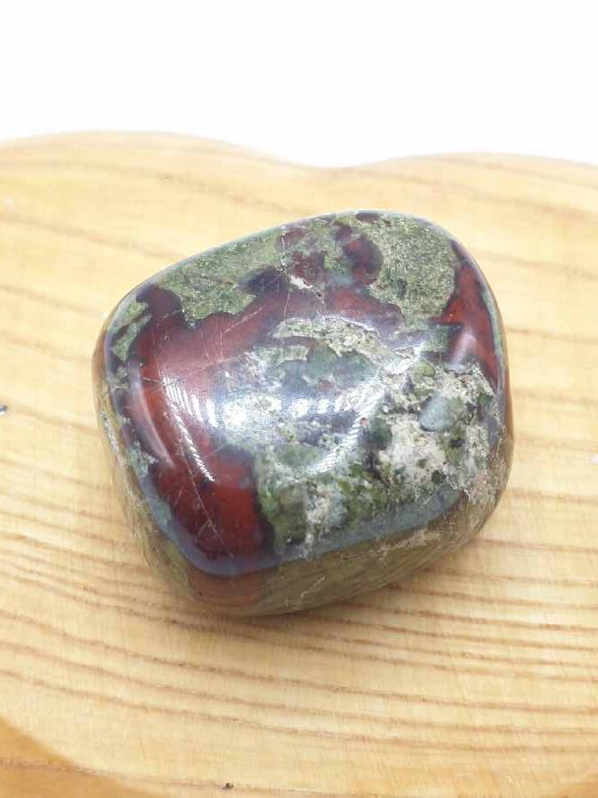 Una pietra di diaspro rosso e verde su una tavola di legno.