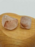 Due sassi di QUARZO EMATOIDE CON TRACCE DI LITHIUM BURATTATO sopra una superficie di legno.