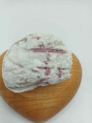 Un pezzo di TORMALINA ROSA O RUBELLITE GREZZA bianca appoggiato su un cuore di legno grezzo.