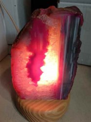 A LAMPADA DI GEODE AGATA 2/3 KG appoggiata su base in legno.