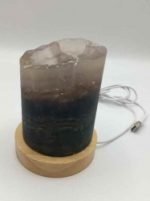 A candle with a piece of quartz on top of a wooden base, embellished with a Rainbow LED Fluorite Lamp with USB cable and includes a USB cable for charging.