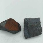 Two pieces of natural raw hematite on a white background.