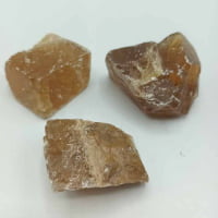 Tre pezzi di quarzo CALCITE MIELE O DORATA GREZZA NATURALE marrone su superficie bianca.