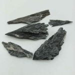 A group of black rocks on a white surface, showcasing natural raw BLACK CYANITE.
