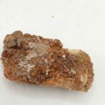 A small piece of RAW VANADINITE on a white surface.