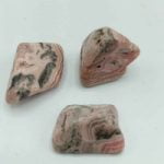 Tre pezzi di diaspro rosa su una superficie bianca, simili a RODOCROSITE BURATTATA.