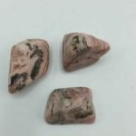 Tre pezzi rosa Rodocrosite Burattata su una superficie bianca.