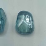 Two pieces of AQUA AURA topaz on a white surface.