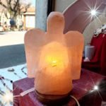 Una piccola "LAMPADA DI SALE ANGELO" seduta su un tavolo davanti ad un negozio, accanto ad una "lampada di sale.