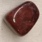 Una pietra rossa PIERTERSITE BURATTATA su una superficie bianca.