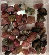 Pink tourmaline crystals in a clear glass container decorated with POLYCHROME TOURMALINE crystals.