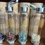 Una collezione di BOTTIGLIE ACQUAGEM PER ELISIR AMETISTA riempie con pietre e cristalli per elisir ametista.
