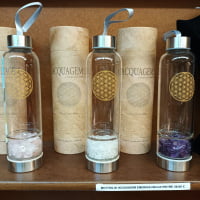 Water ACQUAGEM BOTTLES FOR ROSE QUARTZ ELIXIR with rose quartz stones on shelf.