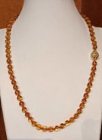 A mannequin adorned with BALTIC AMBER NECKLACE SPHERES.